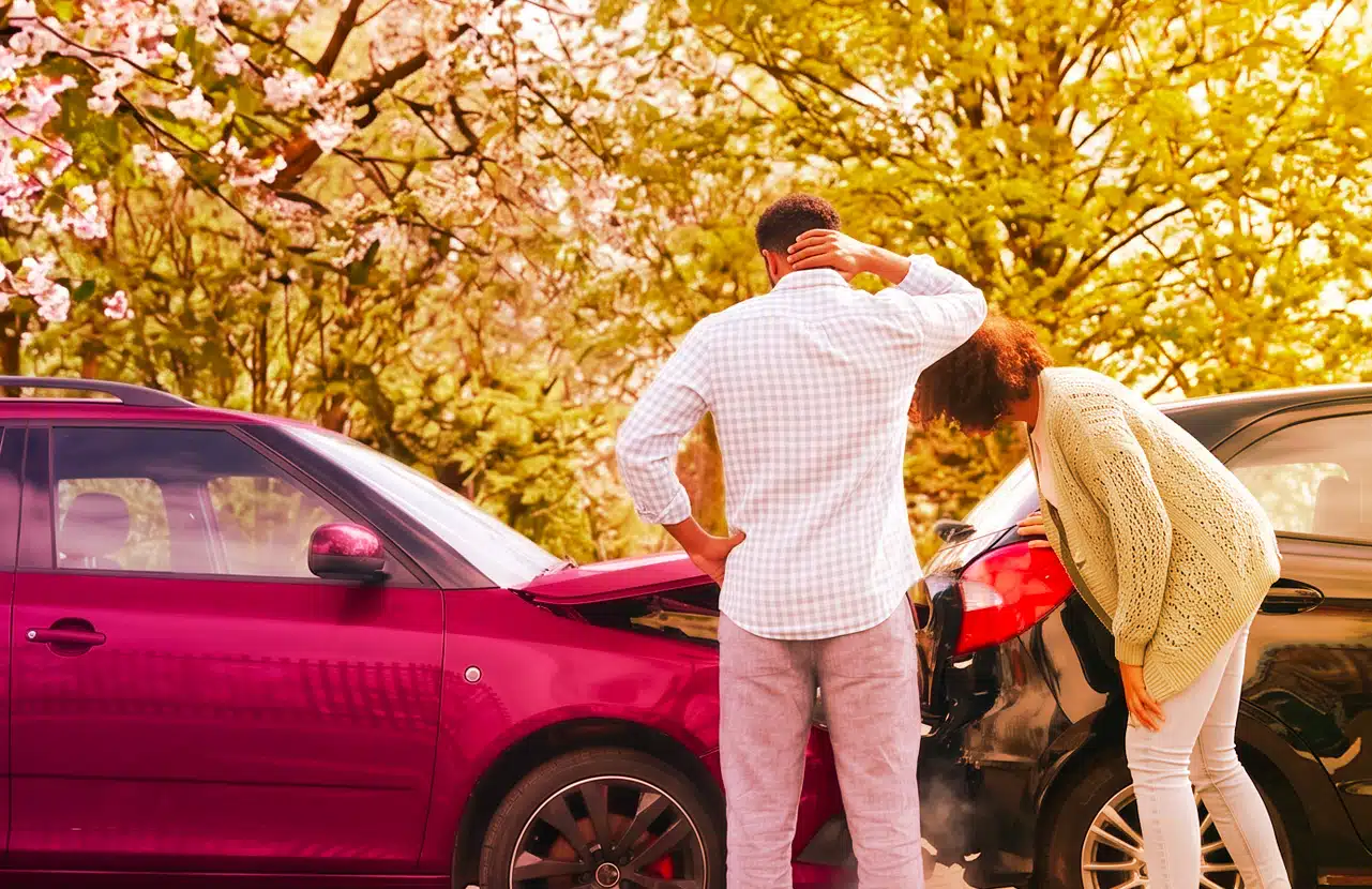 Due persone compilano la constatazione amichevole accanto a un’auto danneggiata dopo un sinistro