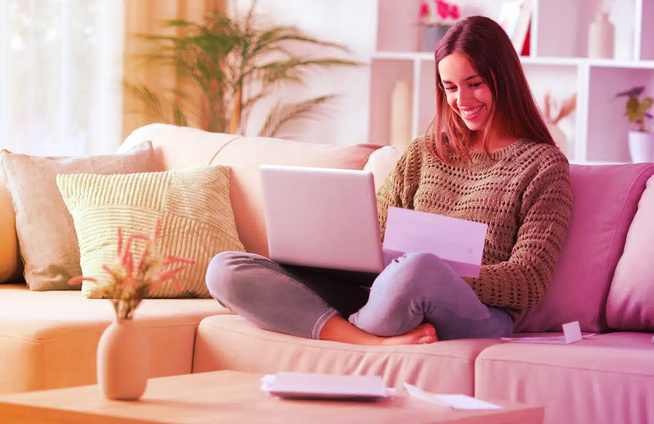 Donna seduta sul divano controlla un preventivo per l’assicurazione casa dal computer portatile
