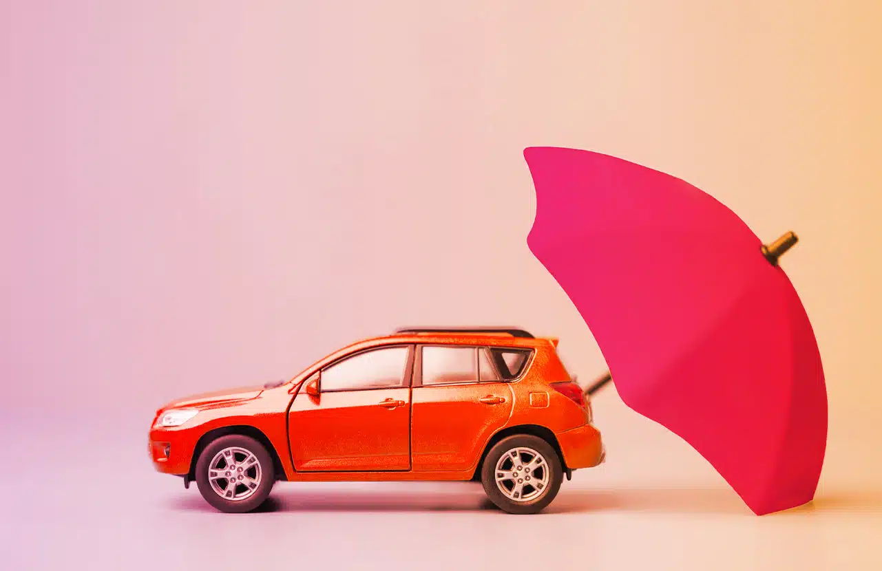 Un’auto giocattolo rossa protetta da un ombrello, a simboleggiare la copertura assicurativa RC Auto
